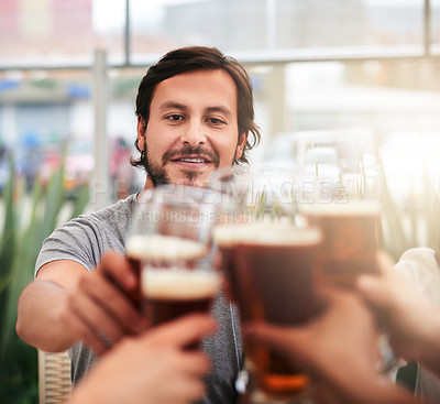 Buy stock photo Shot of a group of cheerful young business colleagues having a celebratory toast with beer around a table outside