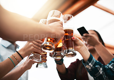 Buy stock photo Low angle shot of a group of young unrecognizable business colleagues having a celebratory toast with beer around a table