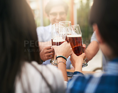Buy stock photo Shot of a group of cheerful young business colleagues having a celebratory toast with beer around a table outside