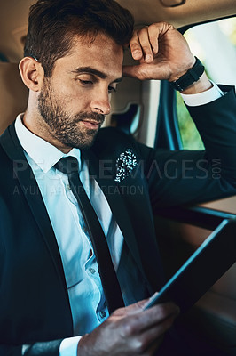 Buy stock photo Cropped shot of a handsome young corporate businessman using a tablet while commuting