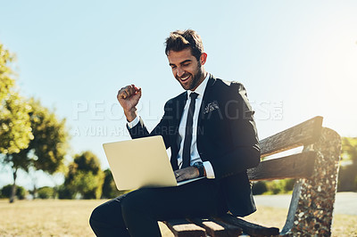 Buy stock photo Cropped shot of a handsome young corporate businessman using a laptop at a public park