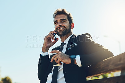 Buy stock photo Cropped shot of a handsome young corporate businessman on a call in a public park