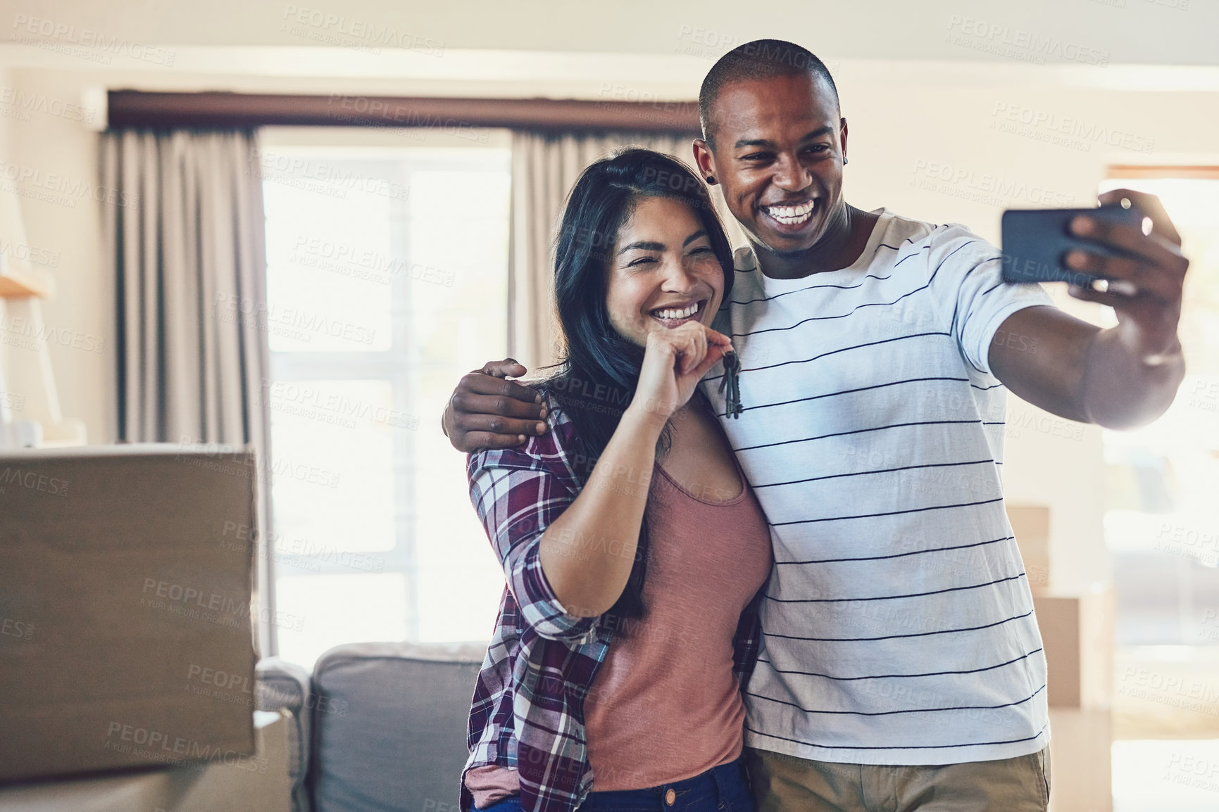 Buy stock photo Shot of a young couple taking a selfie in their new home