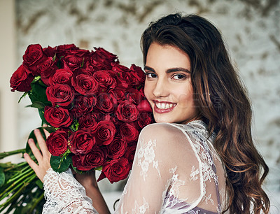 Buy stock photo Portrait of a beautiful young woman relaxing on her bed while holding a bouquet of roses
