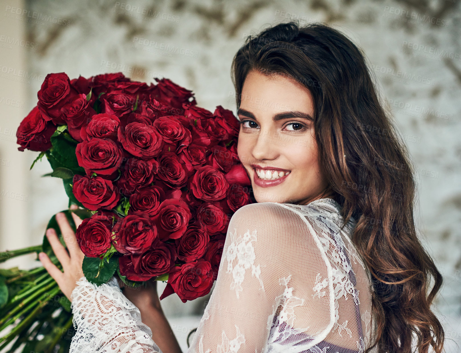 Buy stock photo Portrait of a beautiful young woman relaxing on her bed while holding a bouquet of roses