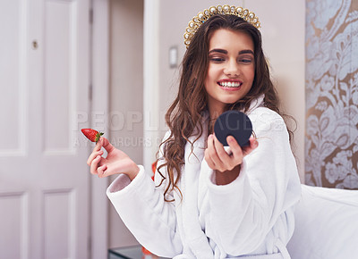 Buy stock photo Shot of an attractive young woman eating a strawberry while looking in a mirror