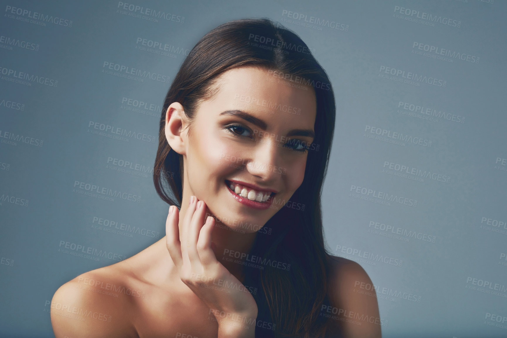 Buy stock photo Studio portrait of a beautiful young woman posing against a blue background