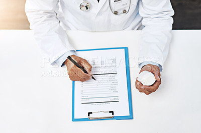 Buy stock photo High angle shot of an unrecognizable male doctor writing on a form while holding medication