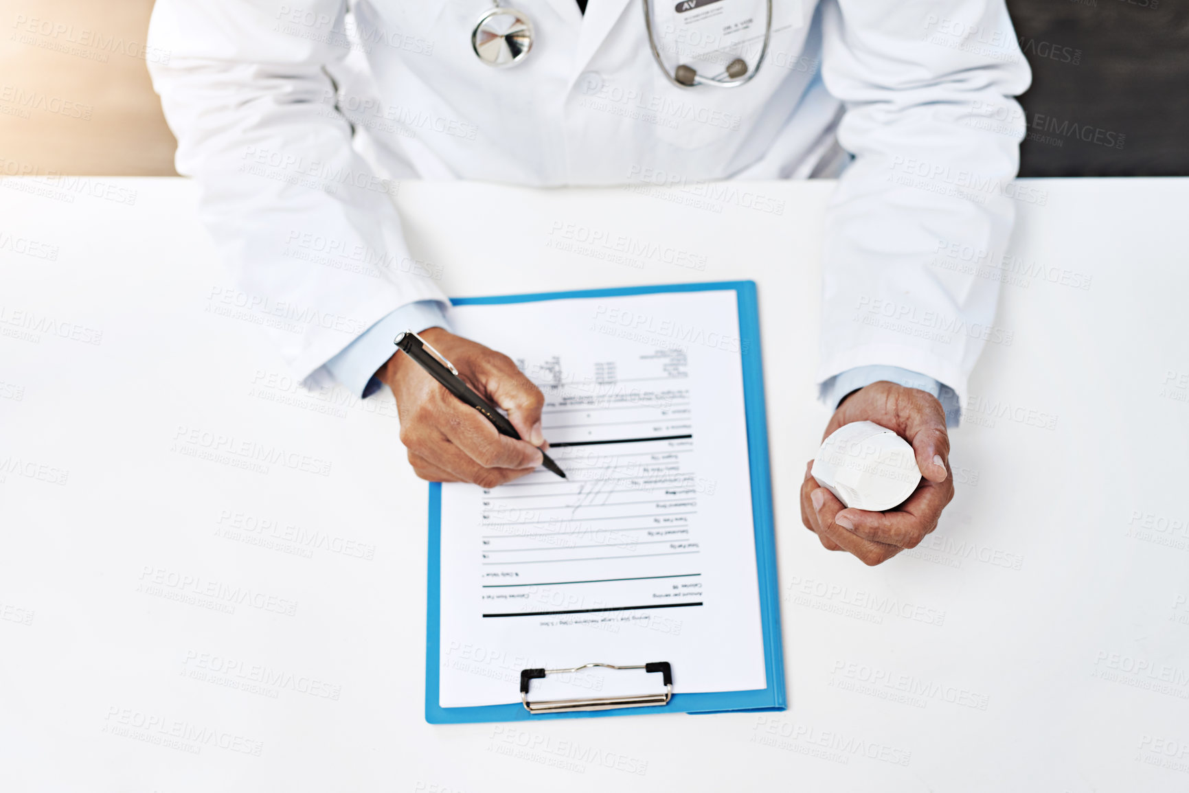 Buy stock photo High angle shot of an unrecognizable male doctor writing on a form while holding medication