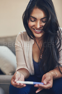 Buy stock photo Shot of a young woman looking happy while taking a pregnancy test at home
