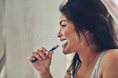 Buy stock photo Shot of an attractive young woman brushing her teeth at home