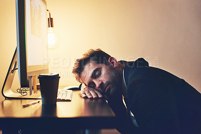 Buy stock photo Cropped shot of a young businessman asleep at his desk during the late shift
