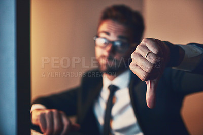 Buy stock photo Cropped portrait of a young businessman giving thumbs down while working late in the office