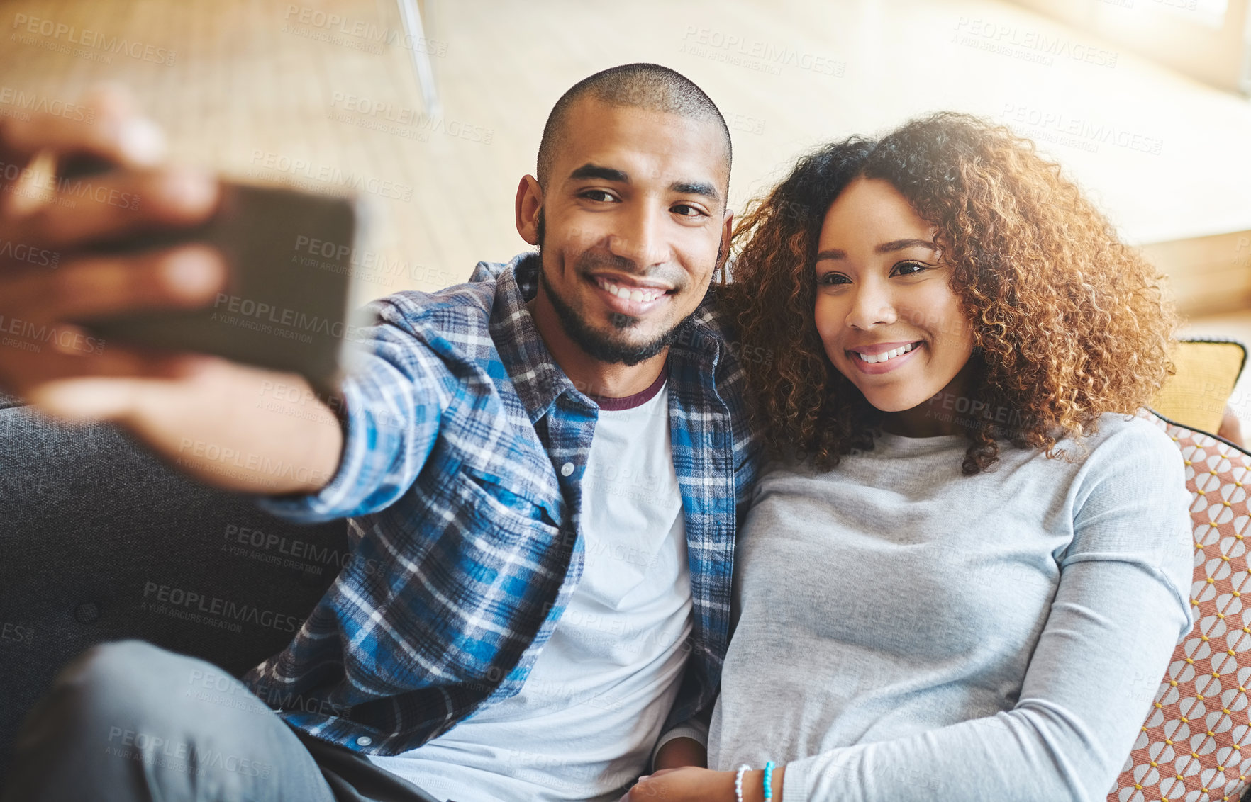 Buy stock photo Smiling couple taking selfie photo on phone together for memories of a romantic relationship while looking relaxed at home. A young trendy dating boyfriend and girlfriend taking a portrait picture