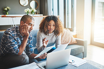 Buy stock photo Shot of a young couple using a laptop and digital tablet while working on their home finances