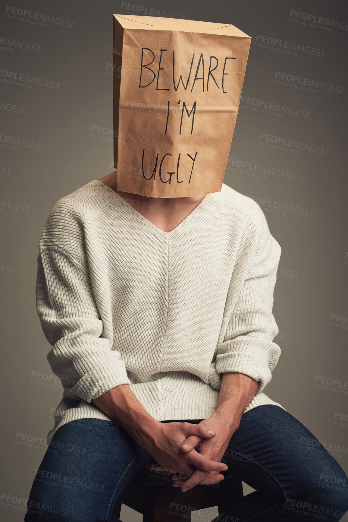 Buy stock photo Studio, person and face with paper bag for cover, insecure and criticism of beauty standards with text. Isolated background, male model and hide with message for protection, shy or lack of confidence