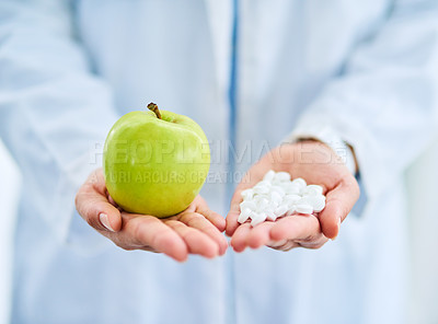 Buy stock photo Closeup shot of an unidentifiable doctor holding an apple and a variety of pills in her hands