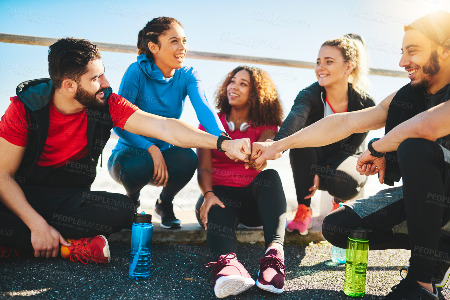 Buy stock photo Shot of a group of young cheerful friends forming a huddle after a fitness exercise outside during the day