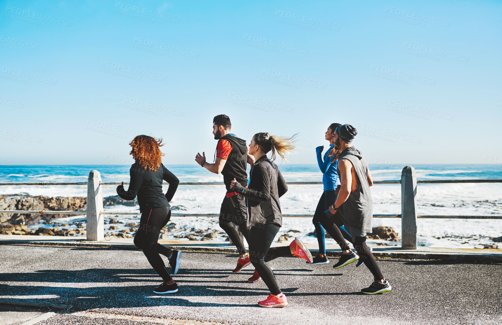 Buy stock photo Shot of a fitness group out running on the promenade