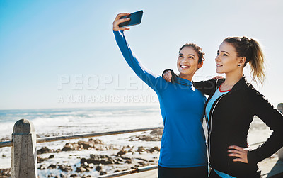 Buy stock photo Cropped shot of two friends taking a selfie while out for a run on the promenade