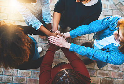 Buy stock photo High angle shot of an unrecognizable group of college friends standing outside with their hands in a huddle