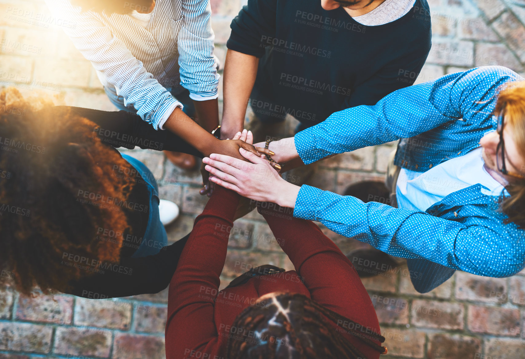 Buy stock photo High angle shot of an unrecognizable group of college friends standing outside with their hands in a huddle