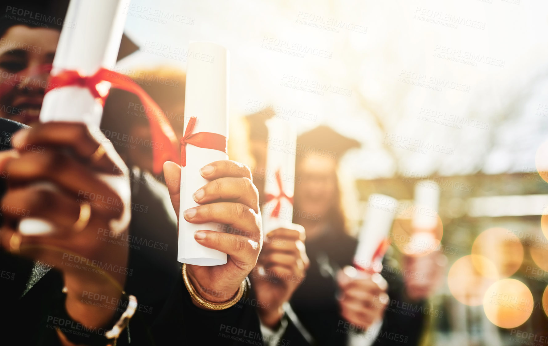 Buy stock photo Cropped shot of a group of students holding their diplomas on graduation day