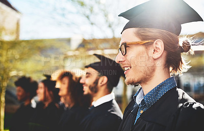 Buy stock photo Shot of a smiling university student on graduation day with classmates in the background