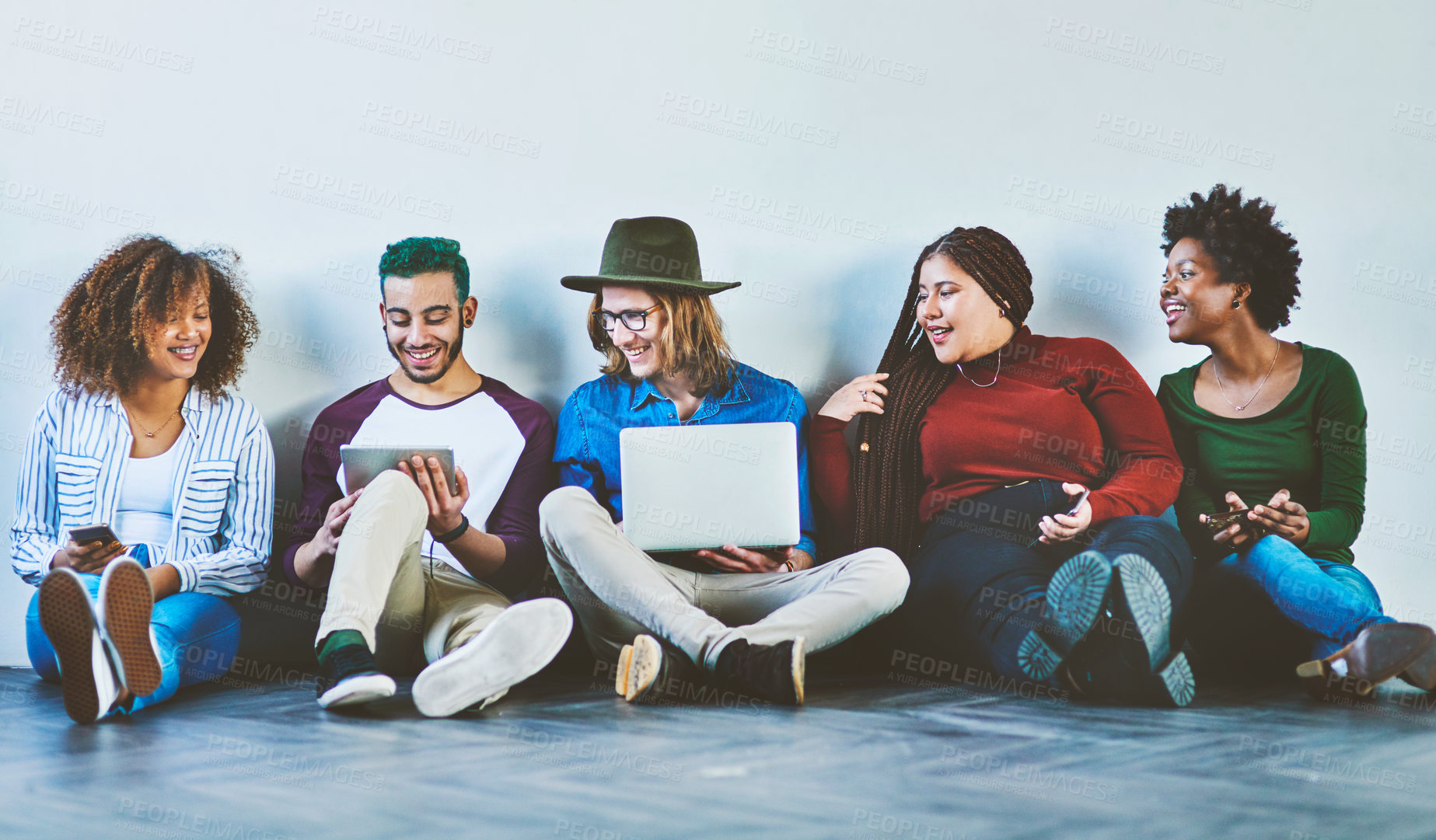 Buy stock photo Studio shot of a group of young people sitting on the floor and using wireless technology