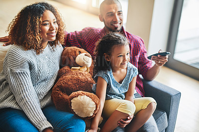 Buy stock photo Shot of a happy young family of three watching tv from the sofa at home