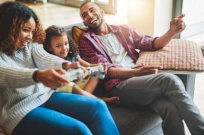 Buy stock photo Shot of an adorable little girl and her parents playing video games together on the sofa at home