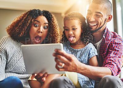 Buy stock photo Shot of an adorable little girl and her parents using a digital tablet together on the sofa at home