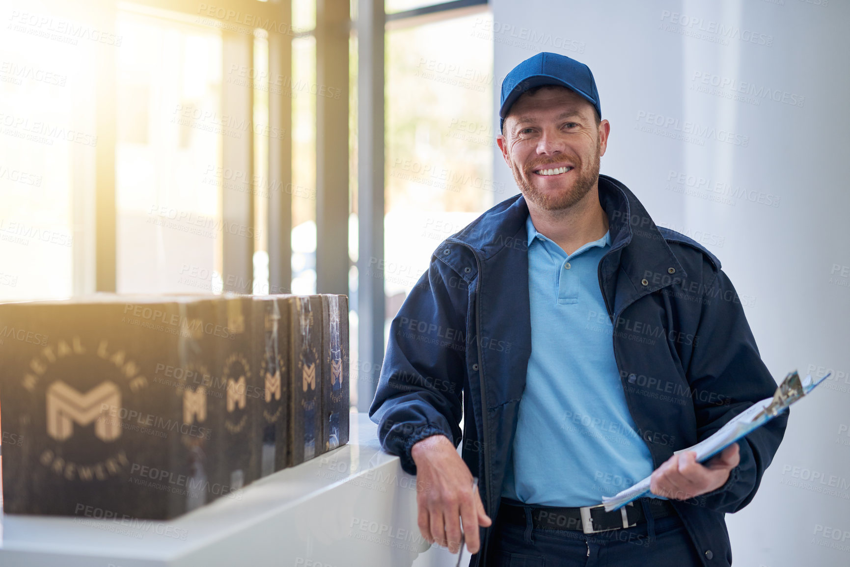 Buy stock photo Cropped portrait of a handsome delivery man waiting in the lobby with a customer's order