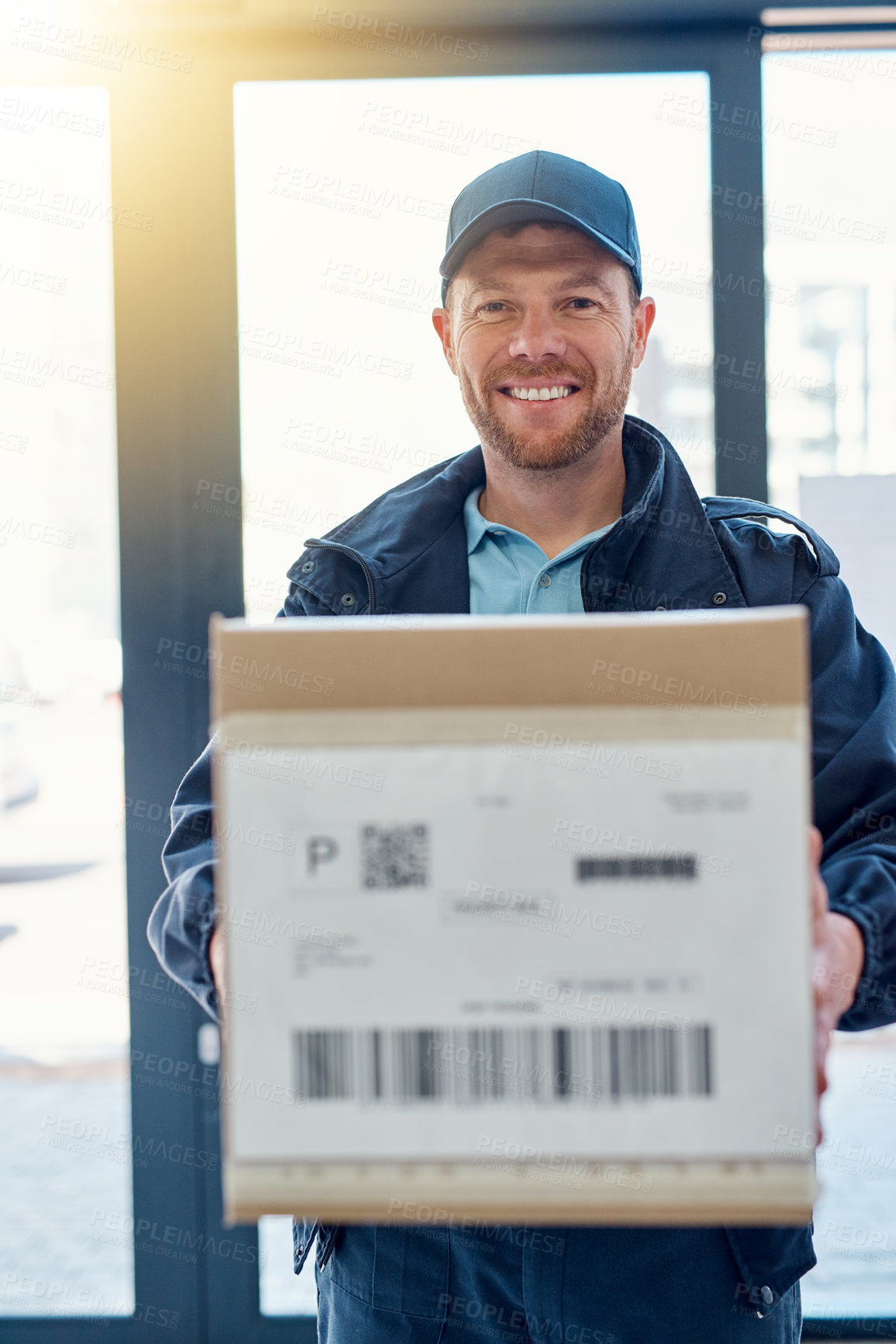 Buy stock photo Cropped portrait of a handsome delivery man waiting in the lobby with a customer's order