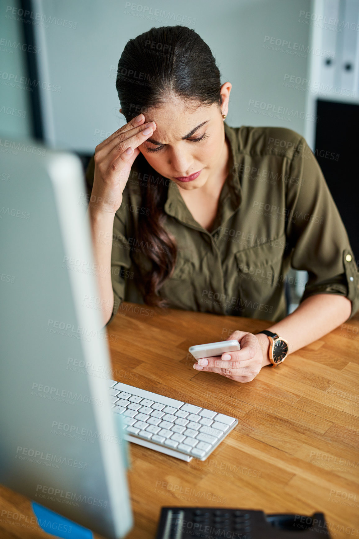 Buy stock photo Shot of a young businesswoman looking stressed out while using a cellphone in an office