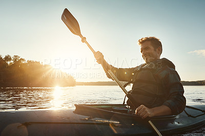 Buy stock photo Shot of a young man kayaking on a lake outdoors