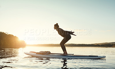 Buy stock photo Shot of an attractive young woman doing yoga on a paddle board on a lake outdoors