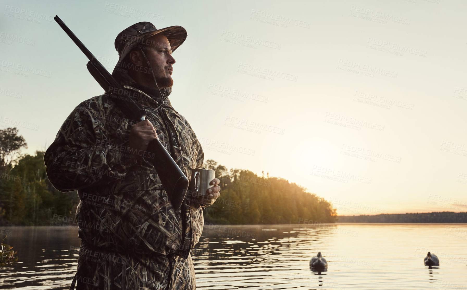 Buy stock photo Shot of a young man hunting duck while dressed in camo outdoors