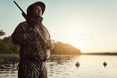 Buy stock photo Shot of a young man hunting duck while dressed in camo outdoors