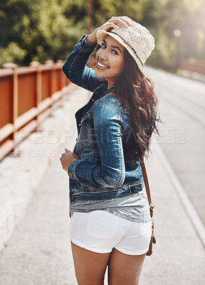 Buy stock photo Shot of a beautiful young woman looking over her shoulder while out for a walk