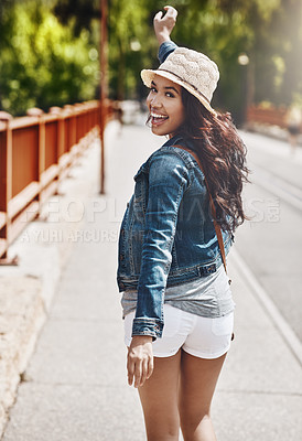 Buy stock photo Shot of a beautiful young woman looking over her shoulder while out for a walk