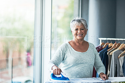 Buy stock photo Portrait of a mature woman ironing clothing at home