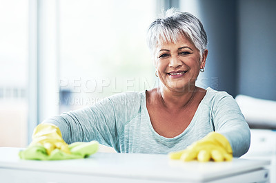 Buy stock photo Portrait of a happy mature woman wearing rubber gloves while cleaning a table at home
