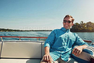 Buy stock photo Shot of a handsome young man spending the day on a private yacht