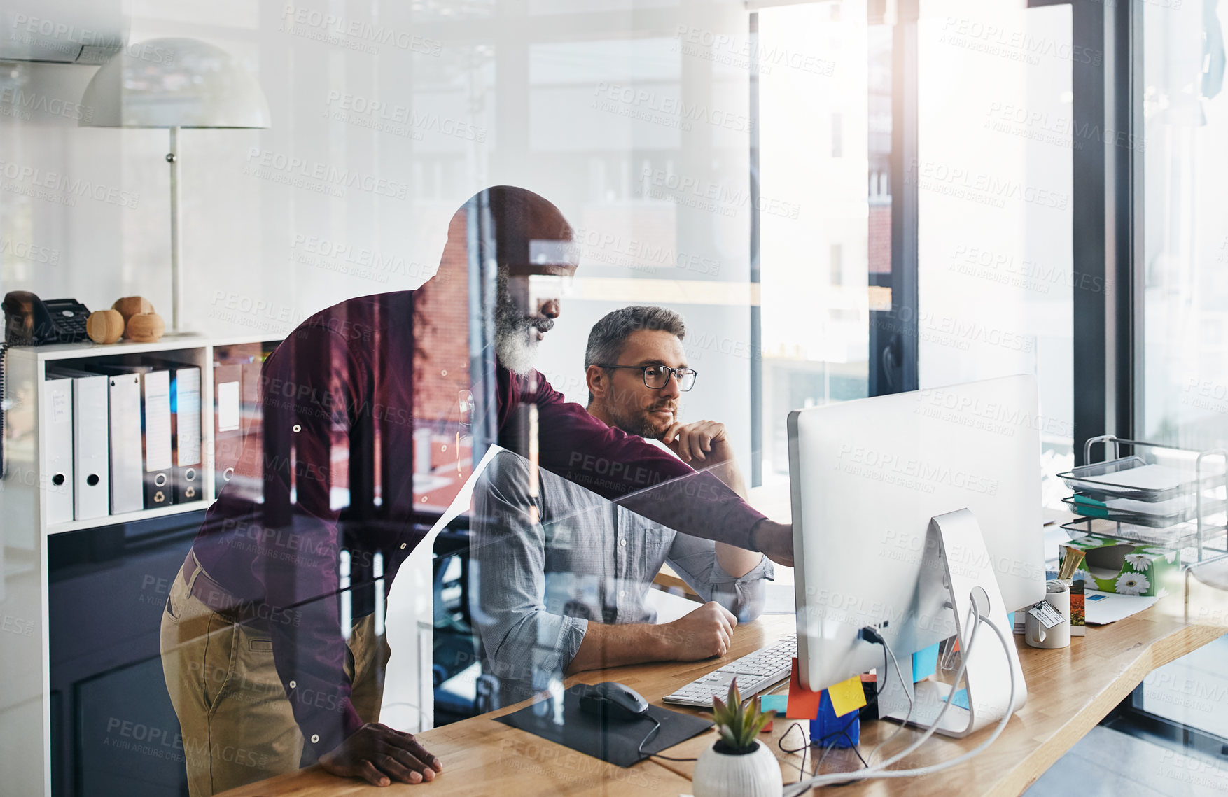 Buy stock photo Shot of two businesspeople working on a computer in an office