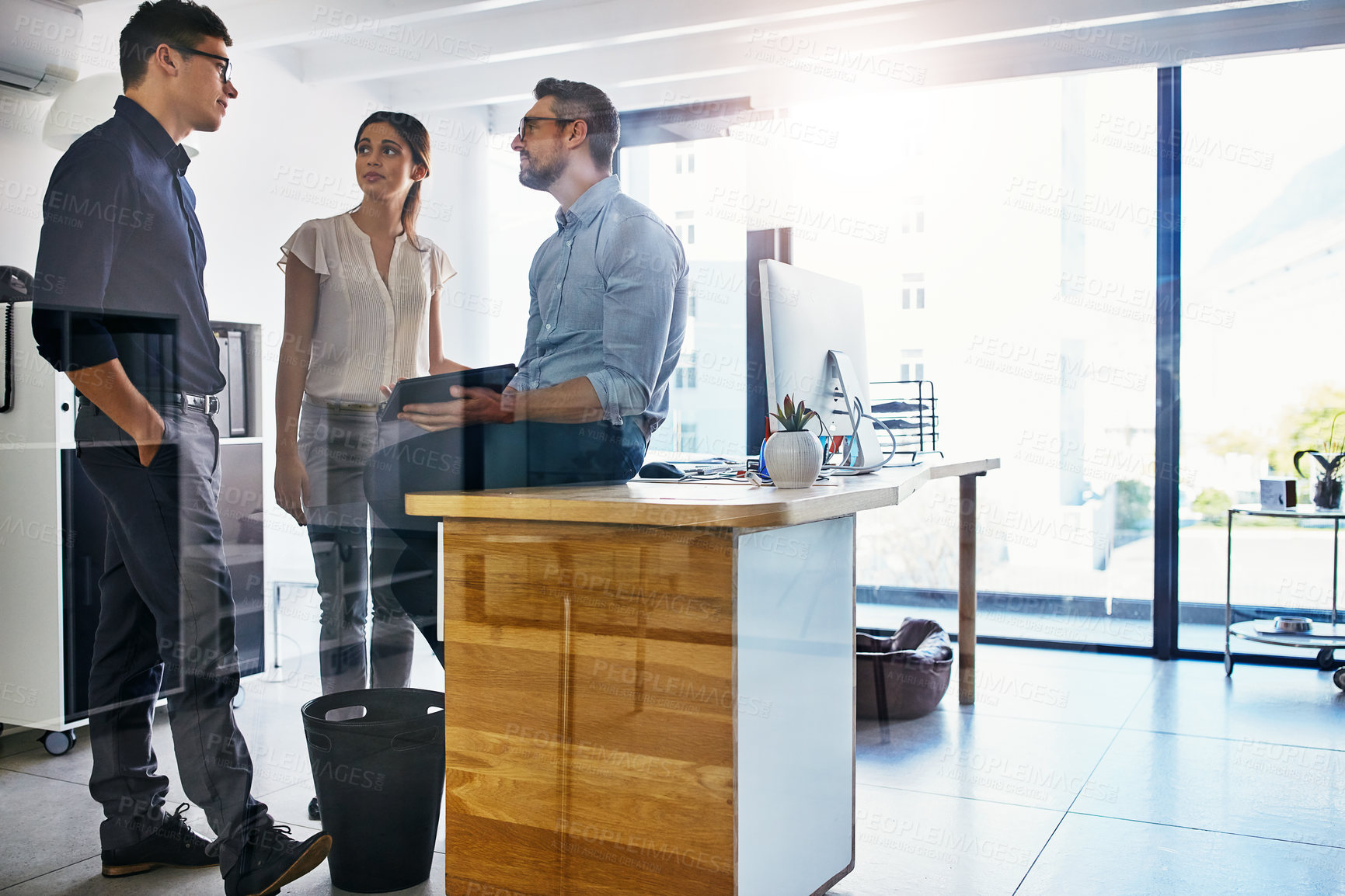 Buy stock photo Shot of a group of businesspeople using a digital tablet in an office