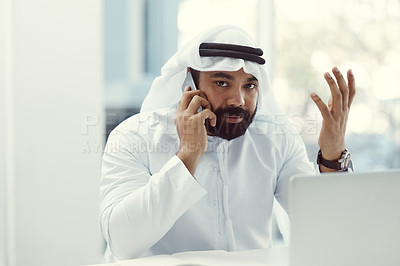 Buy stock photo Cropped portrait of a young businessman dressed in Islamic traditional clothing using his cellphone while working in his office