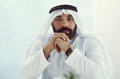 Buy stock photo Cropped portrait of a young businessman dressed in Islamic traditional clothing sitting in his office