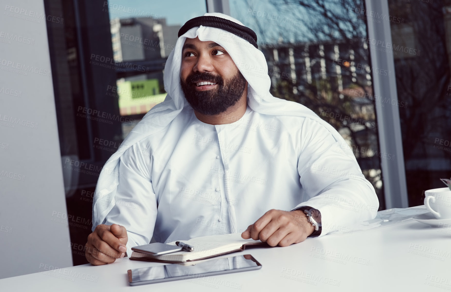 Buy stock photo Cropped shot of a young businessman dressed in Islamic traditional clothing looking thoughtful while working in his office