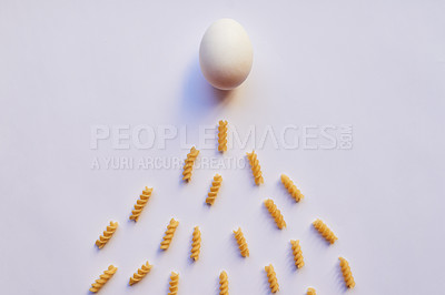 Buy stock photo Studio shot of an egg against a grey background while being surrounded by lots of little pieces of pasta
